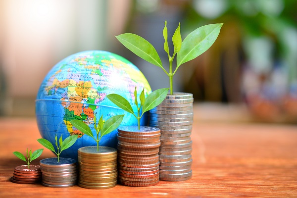 Small globe with stacks of coins and plants